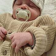 Eden a rejoint le concours — aidez-le/la à gagner de superbes lots ! baby, infant, newborn, sleeping, pacifier, knitted_sweater, beanie_hat, close_up, portrait, cozy, blanket, hand, fingers, button, fabric_texture, indoors, resting, soft_lighting, cute, nursery