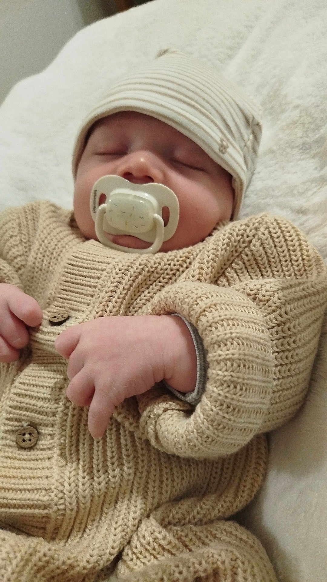 Eden a rejoint le concours — aidez-le/la à gagner de superbes lots ! baby, infant, newborn, sleeping, pacifier, knitted_sweater, beanie_hat, close_up, portrait, cozy, blanket, hand, fingers, button, fabric_texture, indoors, resting, soft_lighting, cute, nursery