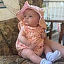 baby, child, infant, hat, dress, socks, couch, indoor, portrait, seated, patterned_fabric, cute, soft_light, skin, person, baby_clothing, summer_hat, plush, small_child, cozy
