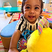 Hethav joined the competition — help win amazing prizes! toddler, child, smiling, face, eyes, toy, stuffed_animal, colorful, indoor, playroom, carpet, clothing, happy, person, furniture, patterned, hand, cute, young_child, portrait