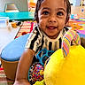 toddler, child, smiling, face, eyes, toy, stuffed_animal, colorful, indoor, playroom, carpet, clothing, happy, person, furniture, patterned, hand, cute, young_child, portrait
