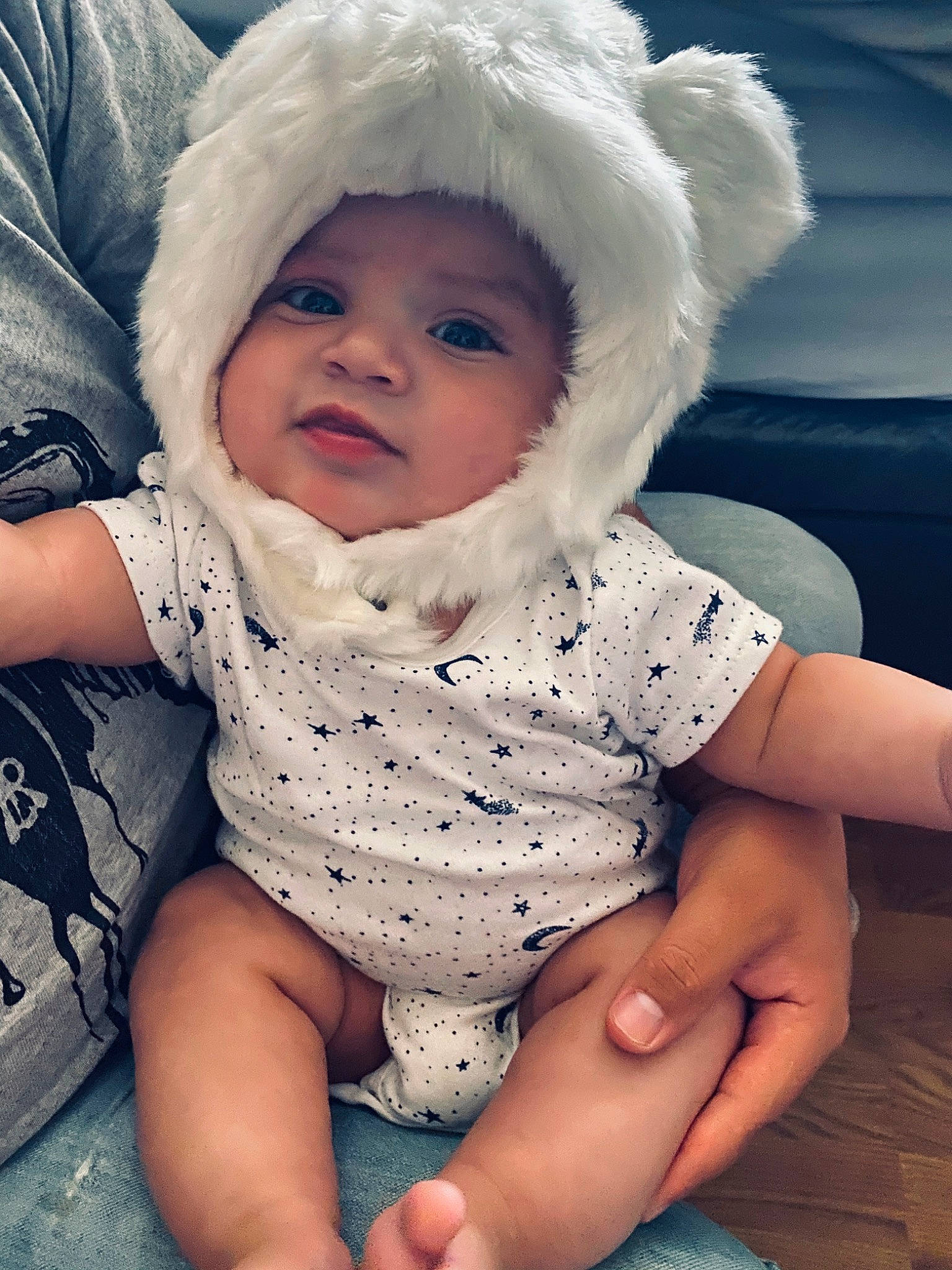 Maliki is registered to the contest to win money with this photo: arm, baby, baby_products, baby_toddler_clothing, bonnet, cheek, child, eye, face, finger, hand, head, headgear, headwear, leg, lip, nose, person, sitting, skin