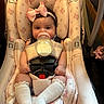 baby, bottle, car_seat, pink_bow, milk, infant, child, sitting, white_socks, floral_pattern, seatbelt, cute, indoors, headband, feeding, small_hands, legs, portrait, baby_clothes, gaze