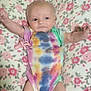 baby, infant, onesie, tie_dye, blanket, floral_pattern, pink, arms_up, lying_down, cute, soft_texture, happy, child, indoors, comfort, newborn, person, skin, smile, cozy