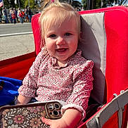 Cheyenne joined the competition — help win amazing prizes! toddler, child, smiling, stroller, red, phone, floral_pattern, outdoor, daylight, face, hair, clothing, hand, park, flag, people, tree, happy, person, cute
