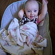 Eliana joined the competition — help win amazing prizes! baby, infant, child, smiling, happy, sitting, portrait, face, eyes, raised_hand, blanket, fluffy_blanket, baby_seat, indoor, wooden_floor, home, cozy, patterned_clothing, looking_at_camera, adorable