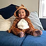 toddler, child, reindeer_costume, onesie, smiling, indoors, couch, blue_couch, pillows, brown_clothing, white_pouch, happy, cute, cozy, window, socks, plush, young_child, home, portrait