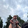 Amir joined the competition — help win amazing prizes! baby, child, arms, tattoo, trees, sky, cloudy, outdoor, nature, person, holding, infant, happy, cute, playful, wristband, shortsleeve, forest, lifting, expression