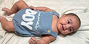 Amir is registered to the contest to win money with this photo: baby, infant, smile, romper, clothing, blue, blanket, soft, cute, child, skin, happy, lying_down, face, cheeks, button, small_hand, indoors, portrait, newborn