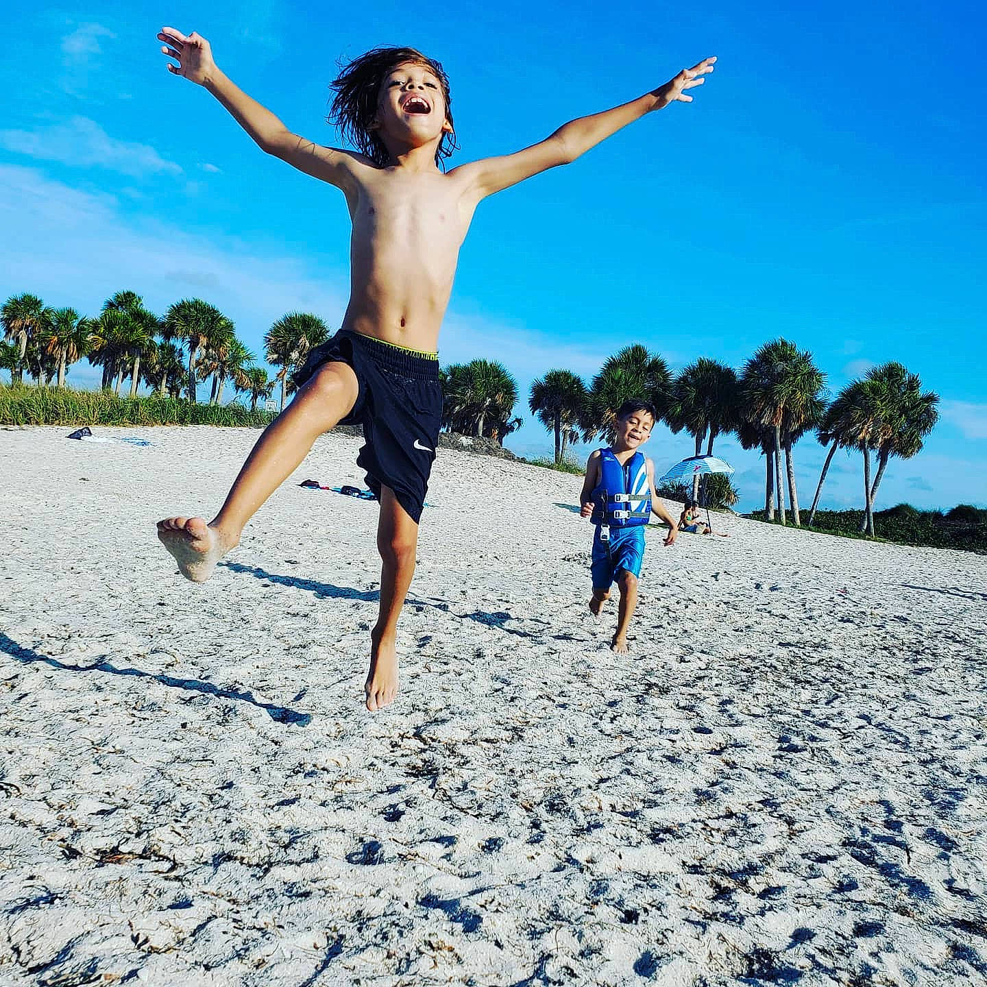Kevin Jr is registered to the contest to win money with this photo: azure, barefoot, beach, body_of_water, cloud, fun, gesture, happy, human_body, leg, leisure, people_in_nature, people_on_beach, person, shorts, sky, sunlight, t_shirt, travel, tree