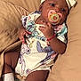 Ciana is registered to the contest to win money with this photo: baby, blanket, bracelet, child, closeup, comfort, cushion, cute, face, hand, headband, indoors, infant, jewelry, lying_down, onesie, pacifier, portrait, skin, socks