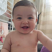 Yara participe au concours pour gagner de l'argent avec cette photo : baby, smiling, indoor, face, child, happy, skin, eyes, mouth, arm, torso, curly_hair, person, cute, infant, natural_light, background, blanket, clothing, room