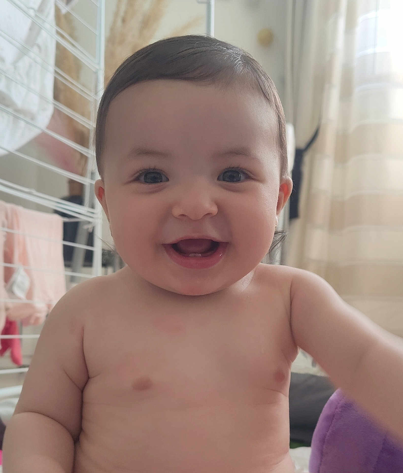Yara participe au concours pour gagner de l'argent avec cette photo : baby, smiling, indoor, face, child, happy, skin, eyes, mouth, arm, torso, curly_hair, person, cute, infant, natural_light, background, blanket, clothing, room
