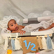 Liam a rejoint le concours — aidez-le/la à gagner de superbes lots ! baby, bathtub, shower_cap, towel, balloons, rubber_duck, milestone, half_year, infant, cute, indoors, celebration, skin, child, toy, white, decor, portrait, smile, relaxation