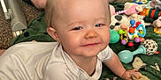 Embri joined the competition — help win amazing prizes! baby, child, crawling, white_onesie, green_blanket, toys, brush, carpet, adult, indoor, smiling, face, playtime, cute, person, floor, happy, head, hand, legs