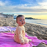 Eïden participe au concours pour gagner de l'argent avec cette photo : baby, beach, blanket, coast, face, head, nature, outdoors, person, photography, portrait, purple, rock, sea, shoreline, sitting, sky, soil, summer, water