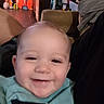 Skyler joined the competition — help win amazing prizes! baby, smiling, face, child, indoor, person, clothing, blurred_background, household_items, orange_wall, happy, portrait, cute, toddler, head, young_child, seated, casual, closeup, expression