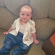 Skyler is registered to the contest to win money with this photo: baby, child, smiling, sitting, couch, clothing, jeans, shirt, tank_top, indoor, person, face, happy, young, cute, cozy, home, relaxed, infant, portrait