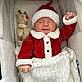 baby, infant, santa_outfit, red_clothing, white_blanket, plush_toy, reindeer_toy, bassinet, cozy, holiday, festive, smiling, cute, child, indoors, blanket, hat, christmas, portrait, newborn
