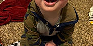 Charlie joined the competition — help win amazing prizes! baby, child, smiling, happy, indoors, carpet, blanket, hoodie, camouflage, feet, hands, door, floor, person, infant, cute, portrait, expression, young, home
