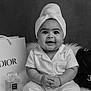 baby, bag, black_and_white, chanel, clothing, cute, dior, fashion, happy, headwrap, indoors, infant, luxury, perfume, portrait, sitting, smiling, soft_lighting, studio, towel