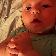 Kayden joined the competition — help win amazing prizes! baby, infant, close_up, face, hands, green_onesie, lying_down, expression, skin, young_child, indoors, blanket, soft_lighting, portrait, cute, person, child, newborn, human, cozy
