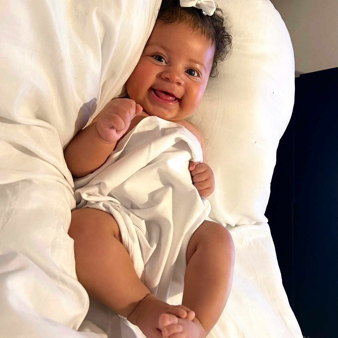 C Ella joined the competition — help win amazing prizes! baby, bed, blanket, child, comfort, cozy, curly_hair, cute, foot, hand, happy, indoors, infant, infant_baby, lying_down, person, portrait, skin, smiling, white_bow