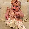 baby, child, girl, smiling, laughing, headband, bow, sitting, couch, blanket, patterned_background, happy, indoors, cute, clothing, white_socks, floral_pants, infant, portrait, cozy