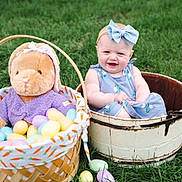 Alyssa is registered to the contest to win money with this photo: baby, child, blue_bow, bucket, grass, easter_eggs, basket, plush_bunny, purple_clothing, outdoor, smiling, happy, spring, cute, headband, sitting, toy, nature, holiday, portrait