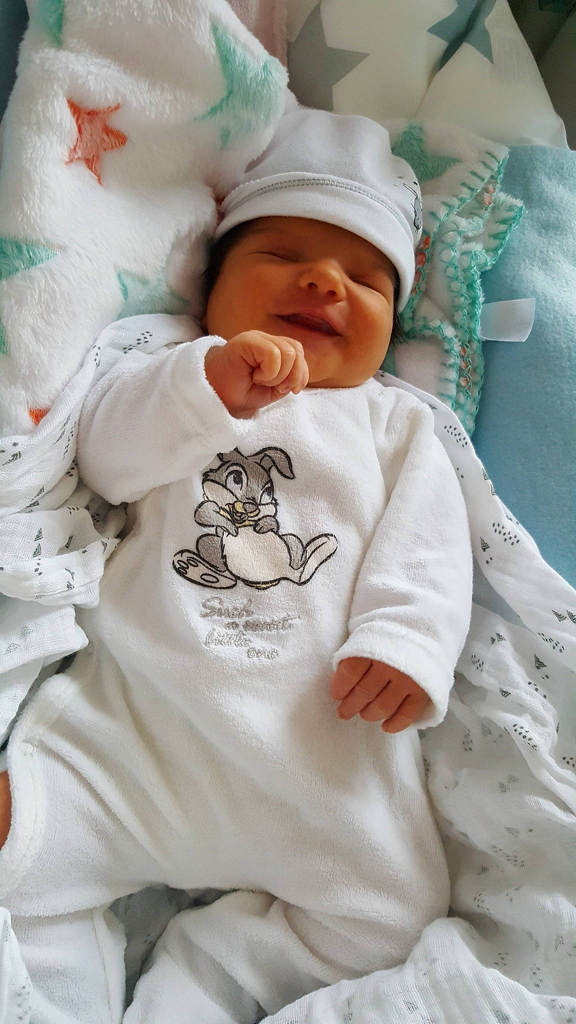Eliza participe au concours pour gagner de l'argent avec cette photo : baby, baby_products, baby_sleeping, baby_toddler_clothing, cap, cheek, child, comfort, happy, hat, head, headwear, linens, pattern, person, skin, sleeve, smile, t_shirt, textile