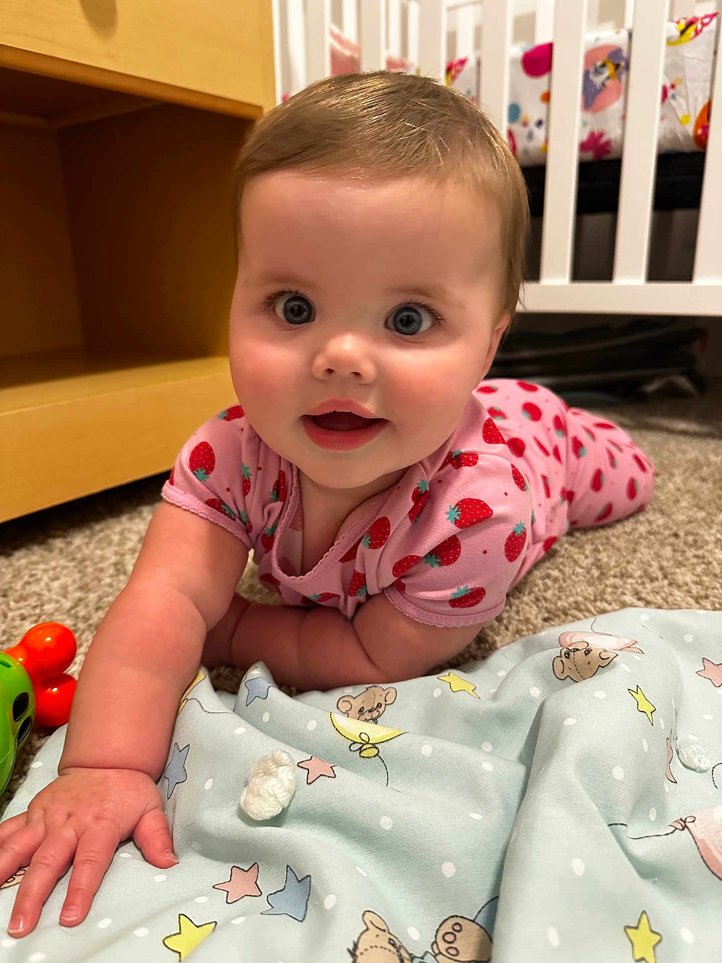 Everly is registered to the contest to win money with this photo: baby, child, crawling, pink_clothing, strawberry_pattern, carpet, toy, nursery, crib, blanket, toddler, cute, indoor, infant, playtime, hand, face, smiling, happy, home