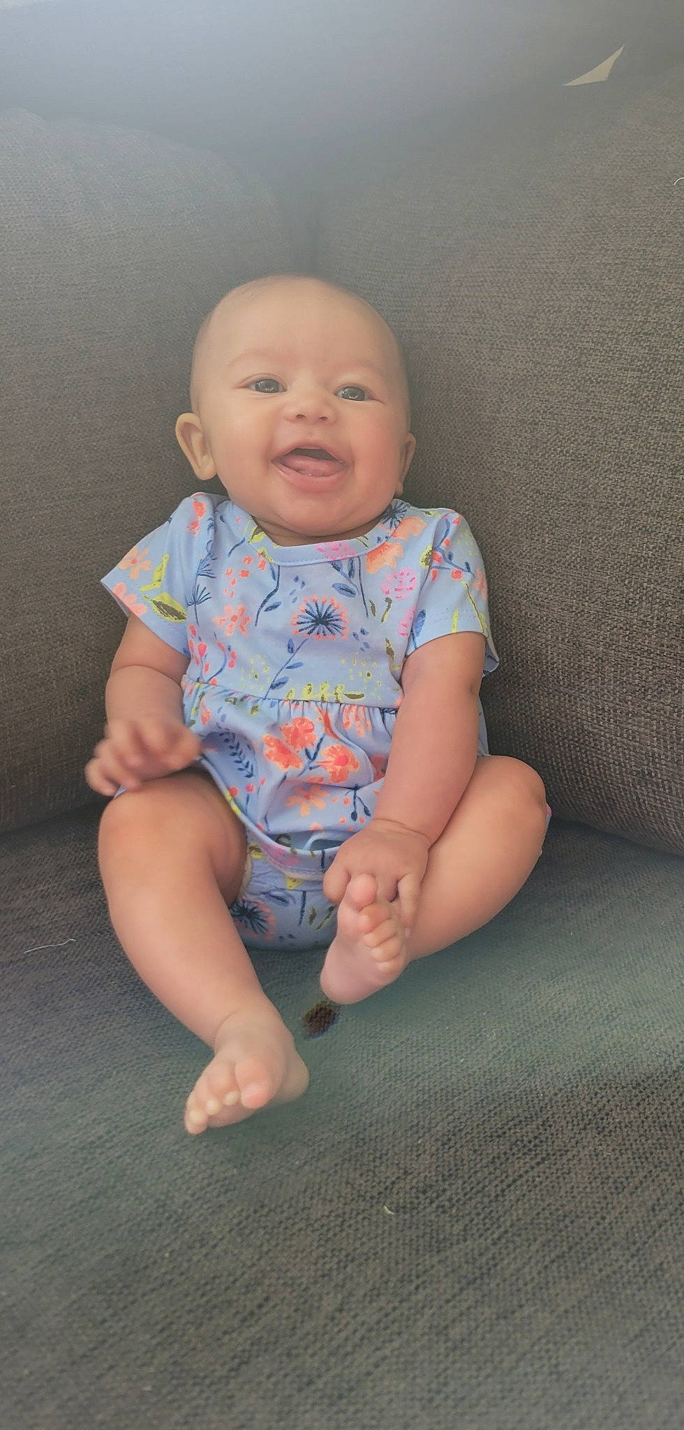 Graelyn is registered to the contest to win money with this photo: baby, baby_toddler_clothing, barefoot, cheek, clothing, comfort, face, finger, floor, flooring, happy, human_leg, iris, nose, person, sitting, skin, sleeve, smile, t_shirt