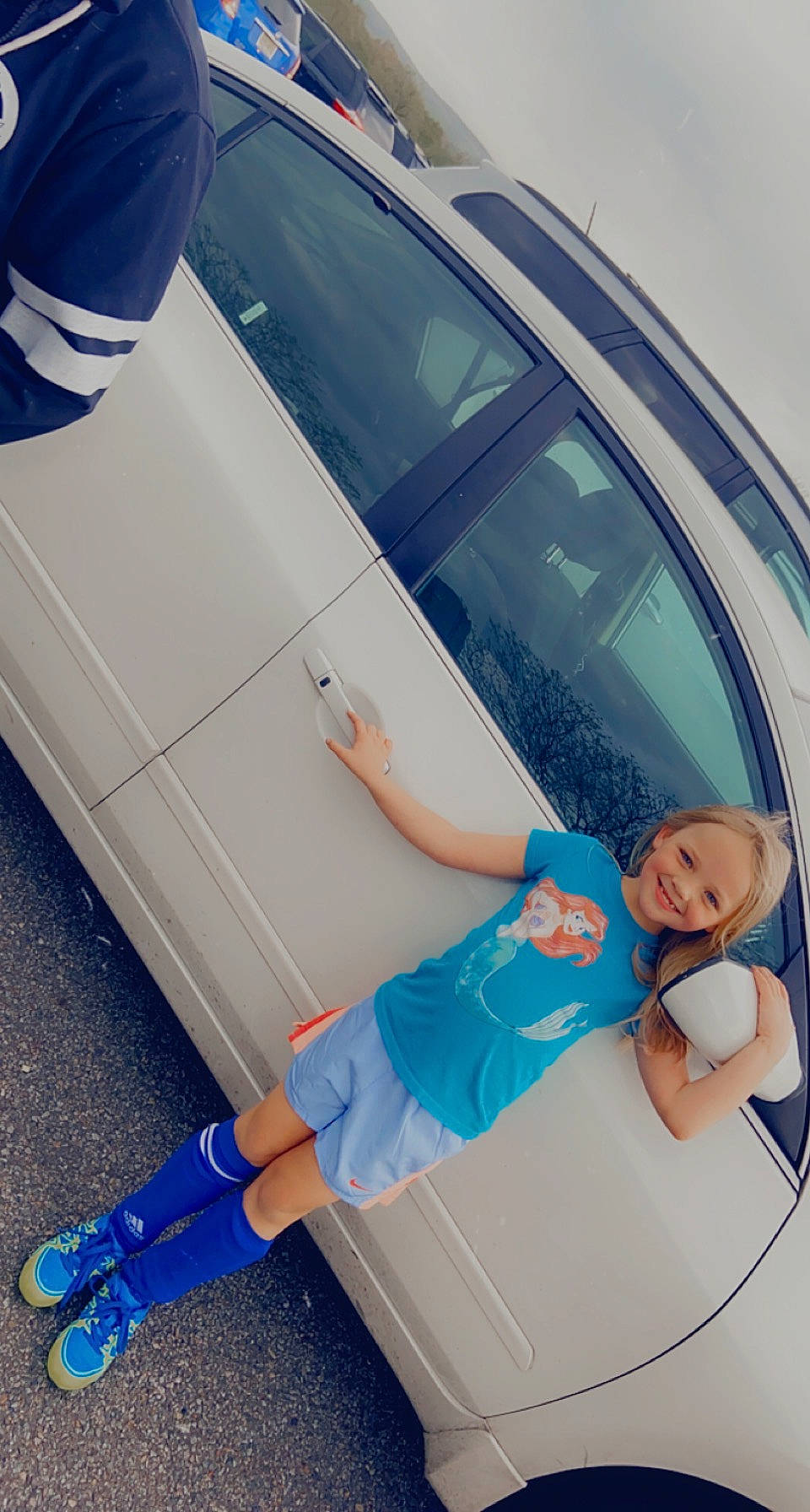 Natalie is registered to the contest to win money with this photo: auto_part, automotive_design, automotive_exterior, automotive_lighting, blue, bumper, car, fender, hood, joy, knee, motor_vehicle, person, personal_luxury_car, shorts, smile, sneakers, tints_and_shades, trunk, vehicle