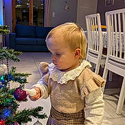 Sélénia participe au concours pour gagner de l'argent avec cette photo : toddler, child, christmas_tree, ornament, holiday, indoor, curious, decorations, plaid_skirt, ruffled_sleeves, cozy, home, furniture, dining_chairs, lights, festive, blonde_hair, floor, curtains, sofa