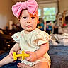 Hazel joined the competition — help win amazing prizes! baby, infant, pink_bow, toy, yellow_toy, indoor, blanket, cute, child, sitting, portrait, clothing, person, face, expression, home, soft_light, cute_baby, playful, young_child