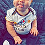 baby, child, infant, headband, orange, bow, tongue, cute, smile, white_socks, black_pants, shirt, text, sitting, blanket, cozy, portrait, face, hands, playful