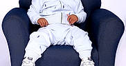 William joined the competition — help win amazing prizes! armchair, baby, blue_clothing, casual, child, comfortable, curly_hair, cute, fashion, indoor, person, portrait, relaxed, seated, smiling, sneakers, studio, toddler, white_background, young_child