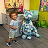 William joined the competition — help win amazing prizes! alphabet_poster, carpet, cat, child, clothing, colorful, desk, green_bag, indoor, marker, office_chair, patchwork, playful, quilt, room, sculpture, smiling, sneakers, toddler, wall_hanging
