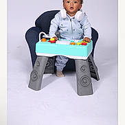 William is registered to the contest to win money with this photo: toddler, child, headphones, toy, keyboard, small_table, blue_chair, studio, white_background, curious, standing, clothing, indoor, play, music, expression, person, young_child, studio_lighting, cute