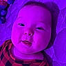 baby, child, infant, portrait, face, eyes, smiling, lying_down, blanket, bed, clothing, checkered_pattern, purple_lighting, indoor, close_up, adorable, head, person, photography, relaxed