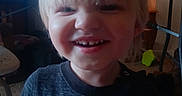 Axel joined the competition — help win amazing prizes! blonde_hair, can, carpet, casual_clothing, chair, child, christmas_tree, face, happy, holiday_lights, indoor, living_room, portrait, shirt, smiling, table, television, text_on_clothing, toddler, toy