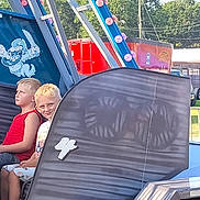 Jacob is registered to the contest to win money with this photo: child, children, boys, carnival_ride, ride_car, number_4, outdoor, daylight, smile, serious, light_bulbs, metal_structure, cartoon, pirate, trees, vehicle, funfair, amusement_park, blond_hair, casual_clothing
