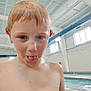 child, boy, indoor_pool, water_drops, wet_skin, tongue_out, short_hair, blue_eyes, playful, swimming, poolside, light, windows, ventilation, ceiling, water, recreation, fun, person, casual