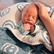 Bohdi is registered to the contest to win money with this photo: newborn, baby, blanket, hand, sleeping, cozy, cute, infant, person, soft, wrapped, smiley_face, comfort, warmth, indoor, portrait, peaceful, tender, love, care