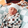 Bohdi is registered to the contest to win money with this photo: newborn, baby, sleeping, blanket, hat, checkered_pattern, cushion, soft, cozy, infant, wrapped, resting, indoors, child, peaceful, cute, portrait, closeup, headwear, fabric