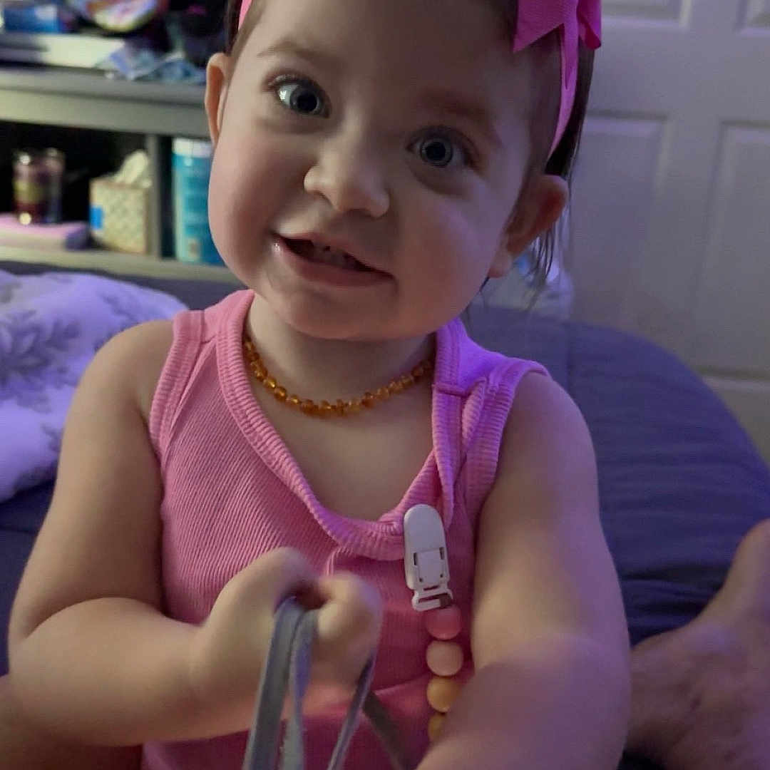 Gabriella is registered to the contest to win money with this photo: accessories, baby, bodypart, clothing, couch, face, finger, furniture, hand, head, indoors, jewelry, medication, necklace, person, photography, pill, portrait, purple, shorts