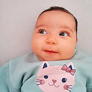 Hayda a rejoint le concours — aidez-le/la à gagner de superbes lots ! baby, infant, portrait, face, eyes, eyelashes, cheeks, smile, sweatshirt, cat_print, bow, soft_lighting, close_up, skin, hair, fabric, cute, indoor, pastel_colors, lying_down