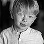 child, boy, portrait, black_and_white, smile, face, eyes, hair, shirt, button_up, young, innocent, expression, close_up, person, photography, blurry_background, soft_lighting, casual_clothing, head_and_shoulders