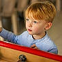 child, boy, indoor, foosball, game, blue_eyes, red_hair, shirt, light_blue, focused, playing, toy, table_game, wood, metal, hand, face, portrait, young, person