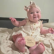 Scarlet joined the competition — help win amazing prizes! baby, infant, smiling, sitting, headband, dress, milestone_sign, six_months, blanket, bed, foot, hand, cute, indoors, child, person, skin, happy, portrait, clothing